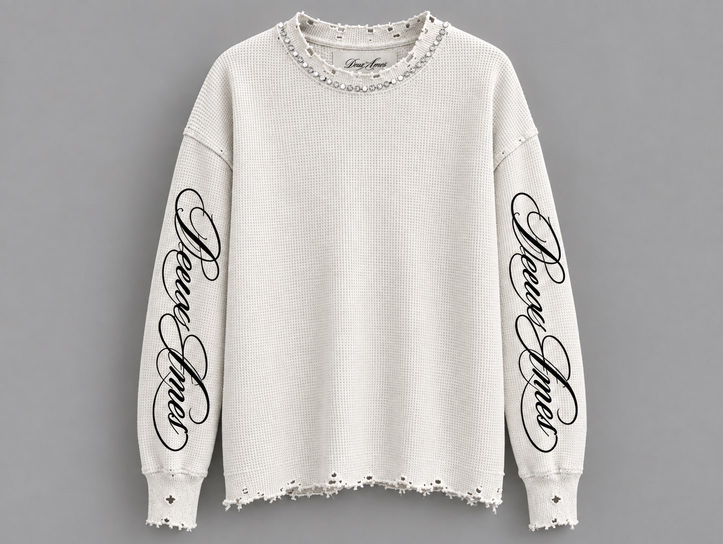 White distressed knit Deux Âmes sweater with crystal neckline and black script sleeves